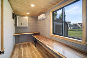 Interior office space with wood ceiling, wood walls, a wall mounted mini split, and light hardwood / wood-style flooring