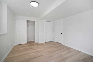 Unfurnished bedroom featuring two closets and light hardwood / wood-style floors