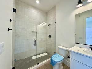 Bathroom with tile patterned flooring, vanity, a shower with door, and toilet