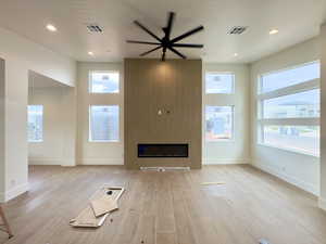 Unfurnished living room with a fireplace, light hardwood / wood-style flooring, and ceiling fan