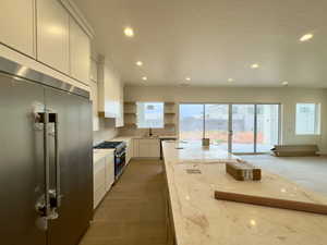 Kitchen featuring light stone counters, white cabinets, dark tile patterned flooring, sink, and premium appliances