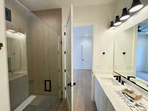 Bathroom with hardwood / wood-style floors, vanity, and walk in shower