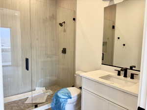 Bathroom featuring vanity, toilet, and a shower with door