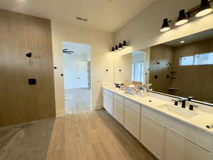 Bathroom featuring a tile shower, hardwood / wood-style flooring, vanity, and ceiling fan