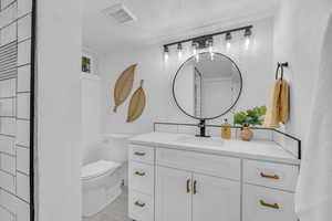 Bathroom with vanity, toilet, and a textured ceiling