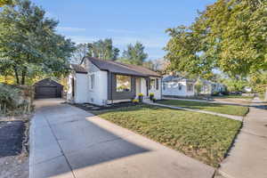 View of front of house with a garage, an outbuilding, and a front lawn