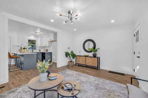 Living room with a notable chandelier, sink, and light hardwood / wood-style flooring