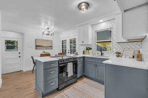 Kitchen featuring kitchen peninsula, light wood-type flooring, a wealth of natural light, and black range with electric stovetop