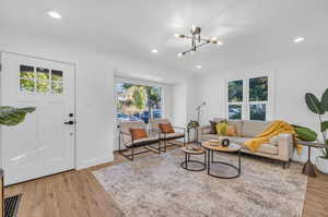 Living room with light hardwood / wood-style flooring, plenty of natural light, and a chandelier