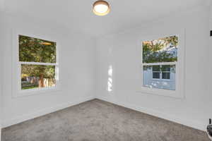 Carpeted empty room featuring ornamental molding