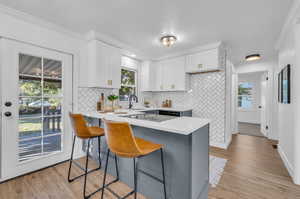 Kitchen with a healthy amount of sunlight, light hardwood / wood-style flooring, and white cabinetry