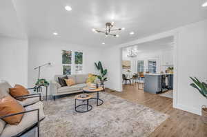 Living room with french doors, light hardwood / wood-style floors, and a notable chandelier