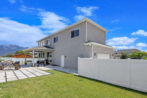 Rear view of house featuring a mountain view, a yard, and a patio