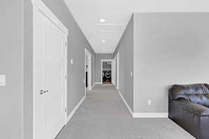 Hallway featuring light carpet, washer / clothes dryer, and a textured ceiling