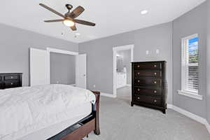 Carpeted bedroom with ceiling fan and connected bathroom