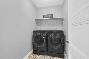 Laundry room featuring washer and dryer, light tile patterned floors, and a textured ceiling