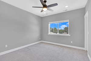 Carpeted spare room with ceiling fan