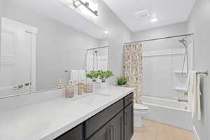 Full bathroom with vanity, toilet, shower / bath combo, a textured ceiling, and tile patterned flooring