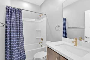 Full bathroom featuring shower / tub combo with curtain, vanity, and toilet