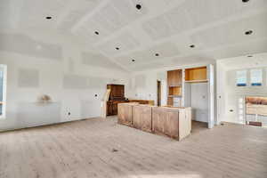 Kitchen with light wood-type flooring, a center island, and high vaulted ceiling