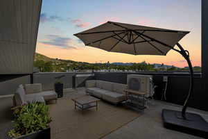 Patio terrace at dusk with a balcony, an outdoor living space, a mountain view, and ac unit