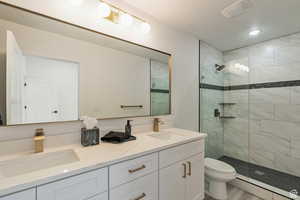 Bathroom with tiled shower, hardwood / wood-style floors, vanity, and toilet