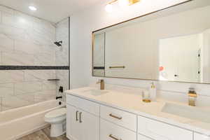 Full bathroom featuring toilet, tiled shower / bath combo, hardwood / wood-style flooring, and vanity