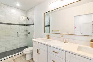 Bathroom featuring vanity, a shower with shower door, and toilet