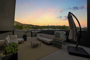 Patio terrace at dusk featuring a mountain view, ac unit, and outdoor lounge area