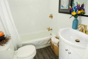 Full bathroom with LVPopen  flooring, shower / bath combination with curtain, vanity, and toilet