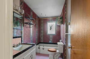 Full bathroom featuring vanity, toilet,  shower combination, tile walls, and tile patterned flooring