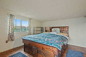 Bedroom with dark parquet floors, vaulted ceiling, and a textured ceiling