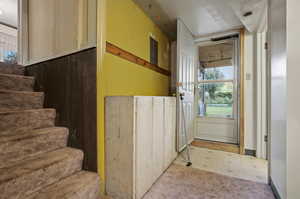 Doorway to outside featuring light colored carpet