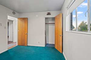 Unfurnished bedroom featuring a closet and dark carpet