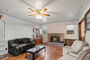 Living room with a fireplace, ceiling fan, hardwood / wood-style floors, and crown molding