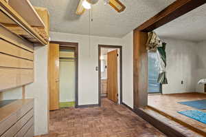 Interior space with ensuite bathroom, ceiling fan, dark parquet flooring, and a textured ceiling