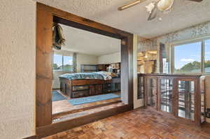 Bedroom with ceiling fan, a textured ceiling, dark parquet floors, and multiple windows