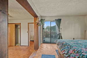 Bedroom with access to exterior, a closet, light parquet flooring, and a textured ceiling