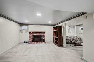 Living room featuring a brick fireplace, crown molding, and carpet flooring