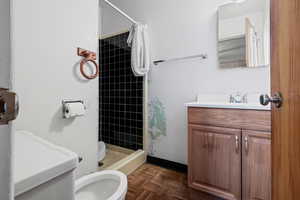 Bathroom featuring parquet floors, a shower with shower curtain, vanity, and toilet