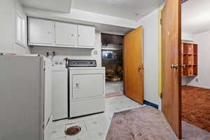 Laundry room with light carpet, cabinets, and washer and dryer