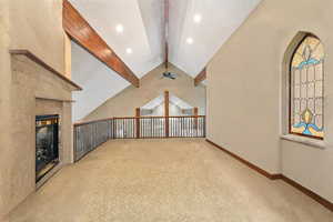 Library , Bonus room featuring a fireplace, light-colored carpet, vaulted ceiling with beams, and ceiling fan