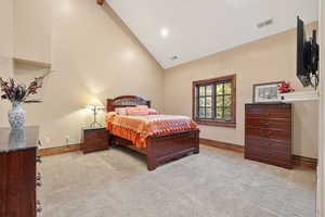 Bedroom featuring light carpet and high vaulted ceiling