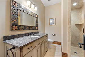 Bathroom with a tile shower, vanity, tile patterned flooring, and toilet