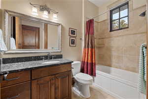 Full bathroom featuring shower / tub combo with curtain, tile patterned floors, vanity, and toilet