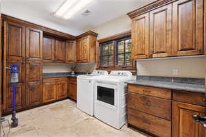 Laundry area featuring washing machine and dryer, a textured ceiling, and cabinets