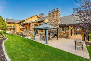 Rear view of house featuring a gazebo, central air condition unit, a patio, and a lawn