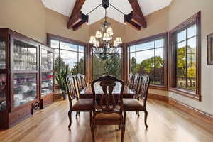 Dining room with a notable chandelier, beamed ceiling, plenty of natural light, and light hardwood / wood-style flooring