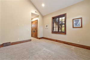 Carpeted empty room with high vaulted ceiling