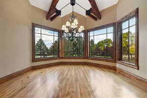 Unfurnished dining area featuring beam ceiling, light hardwood / wood-style flooring, and a wealth of natural light